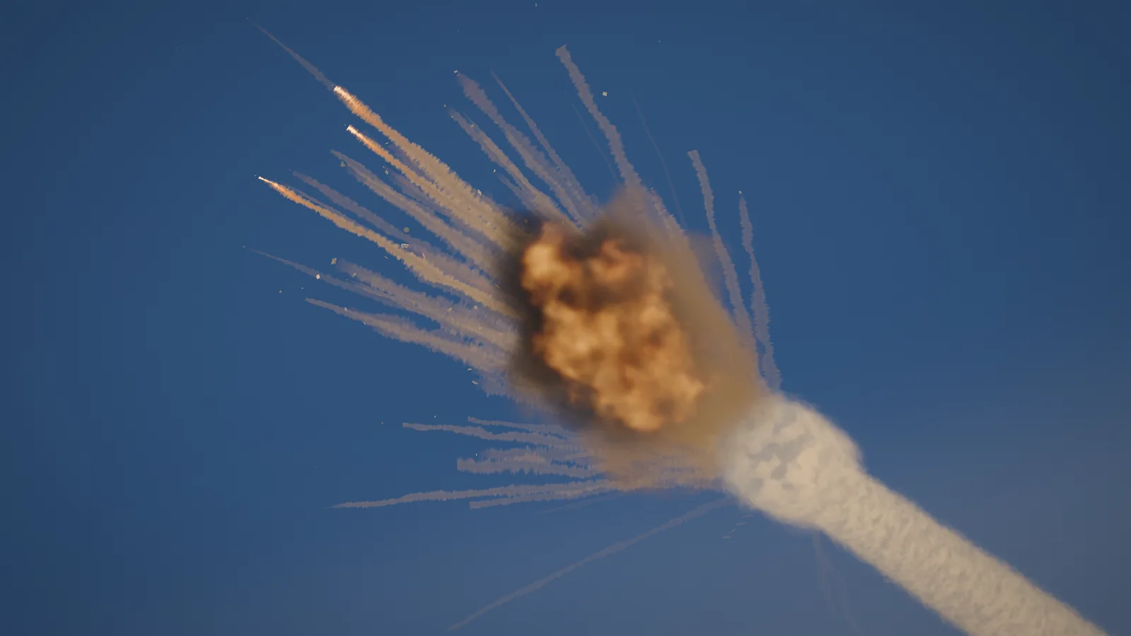 A rocket breaking up during ascent, debris trailing smoke across the sky.